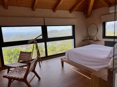 a bedroom with a bed and a chair and large windows at Boutique hotel Urbisol in Calders