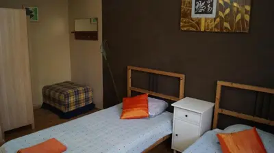 two beds in a small room with two orange pillows at Good-Apartments Barcelona in Barcelona
