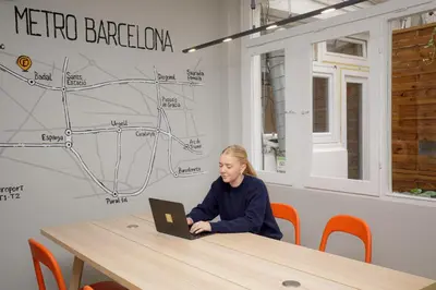 a woman sitting at a table with a laptop at Onefam Les Corts in Barcelona