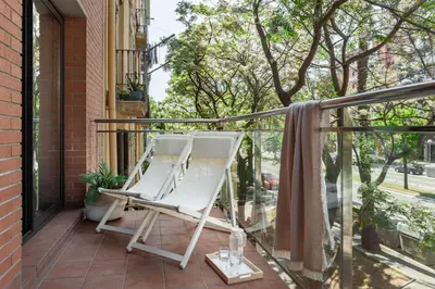 a white chair on a balcony with a window at Apartments Sata Olimpic Village Area in Barcelona