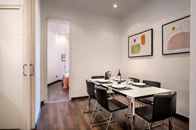 a dining room with a white table and black chairs at Habitat Apartments Eixample Balconies. in Barcelona