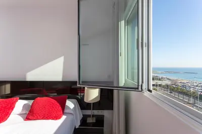 a bedroom with a bed with red pillows and a window at 1410 - Mediterranean Forum Apartment in Barcelona