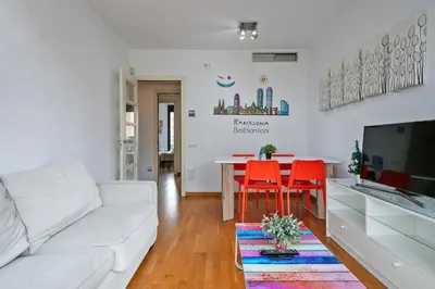 a living room with a white couch and a table with red chairs at 1213 - Ciutadella Nice Apartment in Barcelona