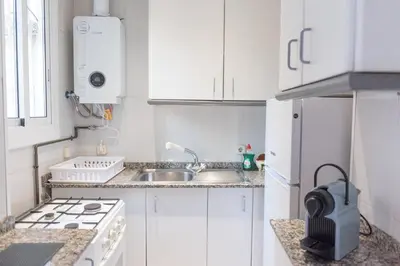 a white kitchen with a sink and a stove at Sweet BCN Studio with Terrace in Barcelona