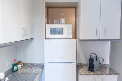 a kitchen with a microwave on top of a refrigerator at Sweet BCN Studio with Terrace in Barcelona