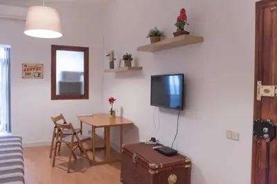 a living room with a table and a tv on a wall at Sweet BCN Studio with Terrace in Barcelona