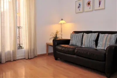 a living room with a leather couch and a table at Apartamentos Bejar in Barcelona