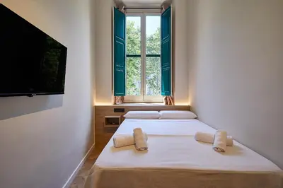 two beds in a room with a window at Ella Hostel Boqueria in Barcelona