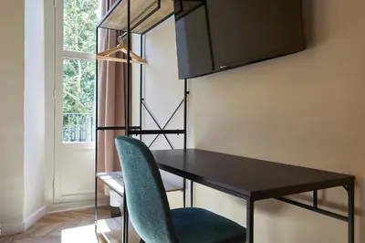 a dining room table with a green chair next to a window at Ella Hostel Boqueria in Barcelona