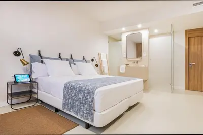 a white bedroom with a large bed and a bathroom at Casa Lirio in Barcelona