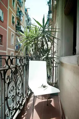 a white chair on a balcony with a plant at Barceloneta Suites Apartments Beach in Barcelona
