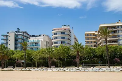 a row of buildings with palm trees and a beach at Hotel Haromar in Calella