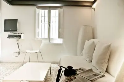 a white living room with a couch and a chair at Barceloneta Suites Apartments Market in Barcelona