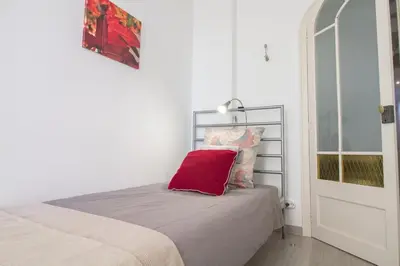a white bedroom with a bed and a window at Armapana in Barcelona