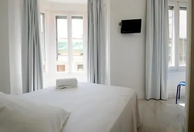 a white bedroom with a bed and a window at Express by gaiarooms in Barcelona