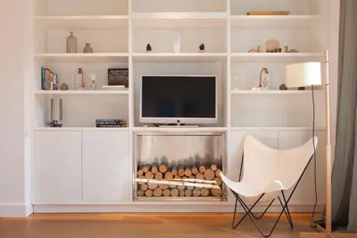 a living room with a fireplace and a white chair at Click&Flat Luxury Sant Joan in Barcelona