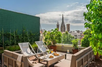 a patio with a table and chairs on a roof at Aspasios Catedral Apartments in Barcelona
