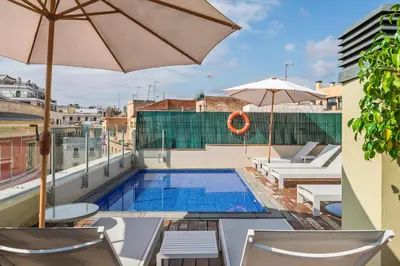 a pool on the roof of a building with chairs and an umbrella at Aspasios Catedral Apartments in Barcelona