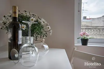 a white table with a bottle of wine and flowers at Hotelito Boutique Badalona. in Badalona