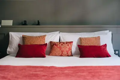 a white bed with four red pillows on it at Circa 1905 in Barcelona