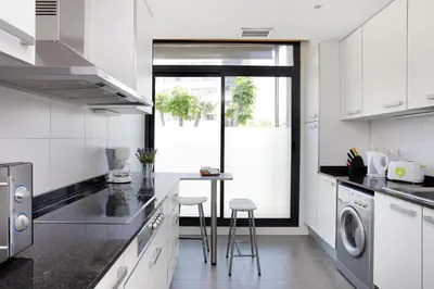 a white kitchen with a table and stools in it at 1215 - Ciutadella Pretty Apartment in Barcelona