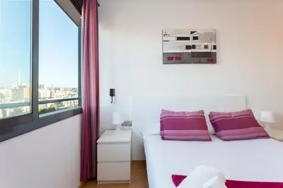 a bedroom with a white bed with purple pillows at 1216 - Forum Gardens Apartment in Barcelona