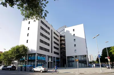 a person riding a bike in front of a building at 1216 - Forum Gardens Apartment in Barcelona