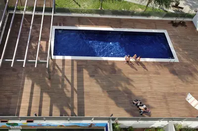 two people sitting on the ledge of a swimming pool at 1217 - POOL AND BEACH NICE APARTMENT II in Barcelona