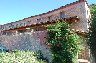 a building with a stone wall with flowers on it at Hotel Moli De La Torre in Bigues i Riells