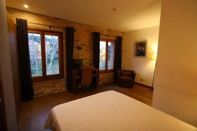 a bedroom with a bed and a desk and windows at Hotel Moli De La Torre in Bigues i Riells