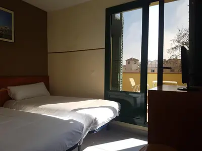 a bedroom with two beds and a large window at El Jardi in Barcelona
