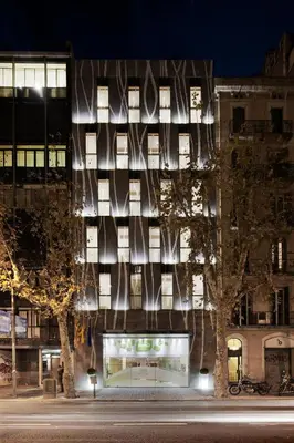 a building with a facade with windows at night at Ako Suite Hotel in Barcelona