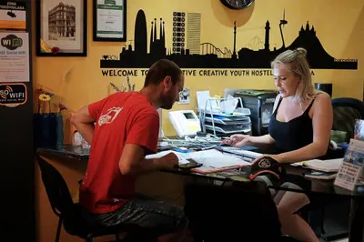 a man and a woman sitting at a desk at Alternative Creative Youth Hostel Barcelona in Barcelona