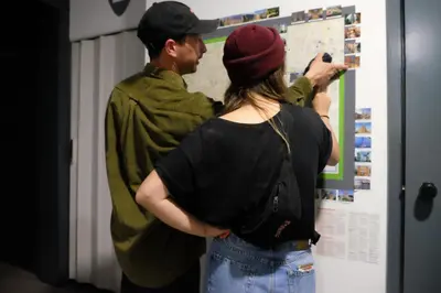 a man and woman looking at a poster on a wall at Alternative Creative Youth Hostel Barcelona in Barcelona
