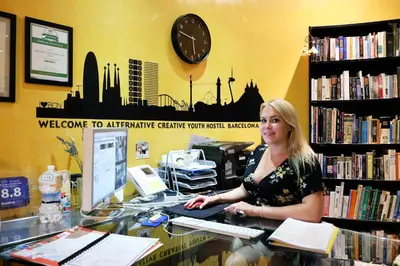 a woman sitting at a desk in a library at Alternative Creative Youth Hostel Barcelona in Barcelona