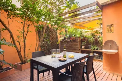 a table and chairs on a patio with trees at Montaber Apartment - Trafalgar in Barcelona