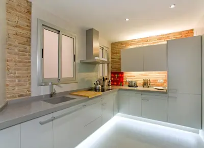a kitchen with white cabinets and a brick wall at Montaber Apartment - Bailén in Barcelona