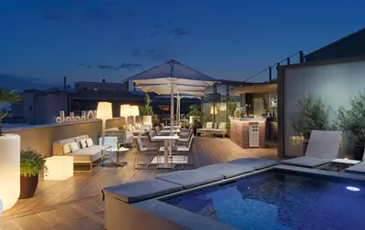a rooftop patio with a pool and tables and chairs at H10 Casanova in Barcelona