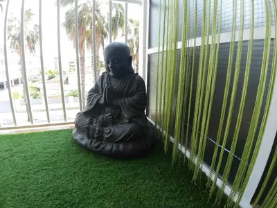 a statue of a buddha sitting on the grass at Family Deluxe Apartment Beach in Castelldefels