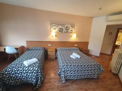 a room with two beds and a table at Hostal Rio De Castro in Barcelona