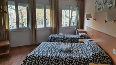 two beds in a hotel room with windows at Hostal Rio De Castro in Barcelona