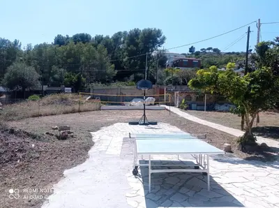 a patio with two chairs and trees and a building at Casa Calafell in Segur de Calafell