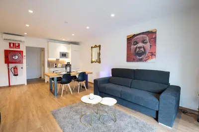 a living room with a blue couch and a kitchen at Airhostel Barcelona Airport 24h in El Prat de Llobregat