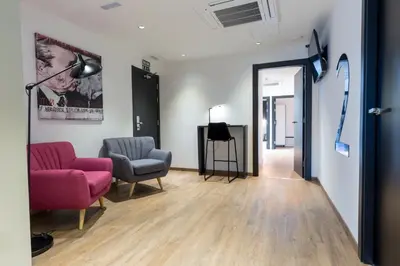 a living room with two chairs and a pink couch at Airhostel Barcelona Airport 24h in El Prat de Llobregat