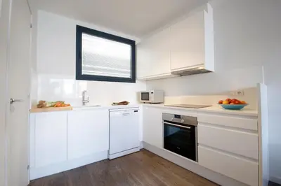 a white kitchen with white cabinets and a window at Decô Apartments Barcelona-Diagonal in Barcelona