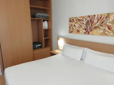 a bedroom with a white bed and a painting on the wall at Aura Park Aparthotel Fira Barcelona in Hospitalet de Llobregat