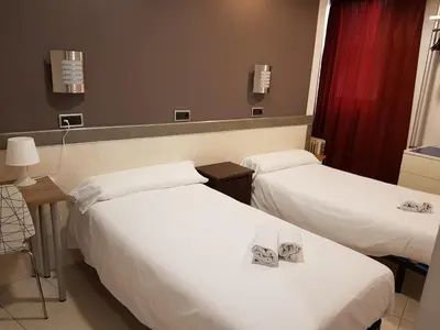 two beds in a hotel room with white sheets at Hostal Levante Barcelona in Barcelona