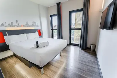 a bedroom with a large white bed and a tv at easyHotel Barcelona Fira in Hospitalet de Llobregat