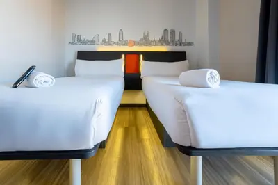 two twin beds in a room with wooden floors at easyHotel Barcelona Fira in Hospitalet de Llobregat