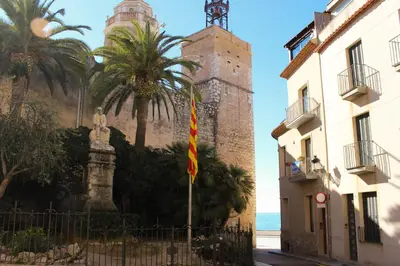 a building with a clock tower and palm trees at Sitges Apartment in Sitges